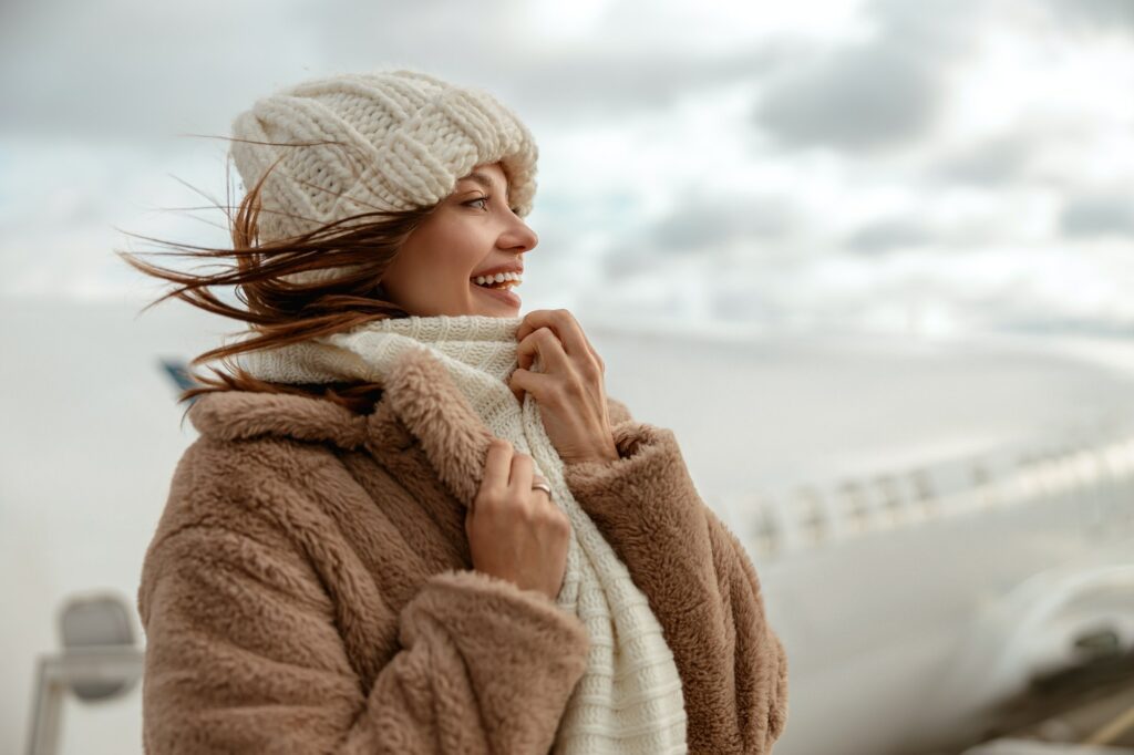 Cheerful woman in knitted hat standing outdoors at Atlanta airport