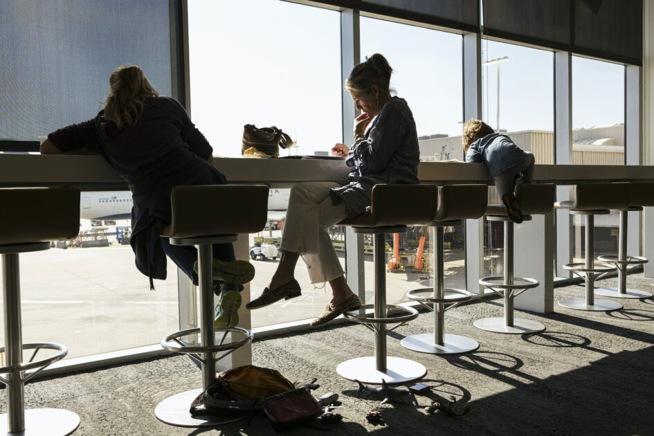 A mature woman and two children seated on high stools at an Atlanta airport departure lounge
