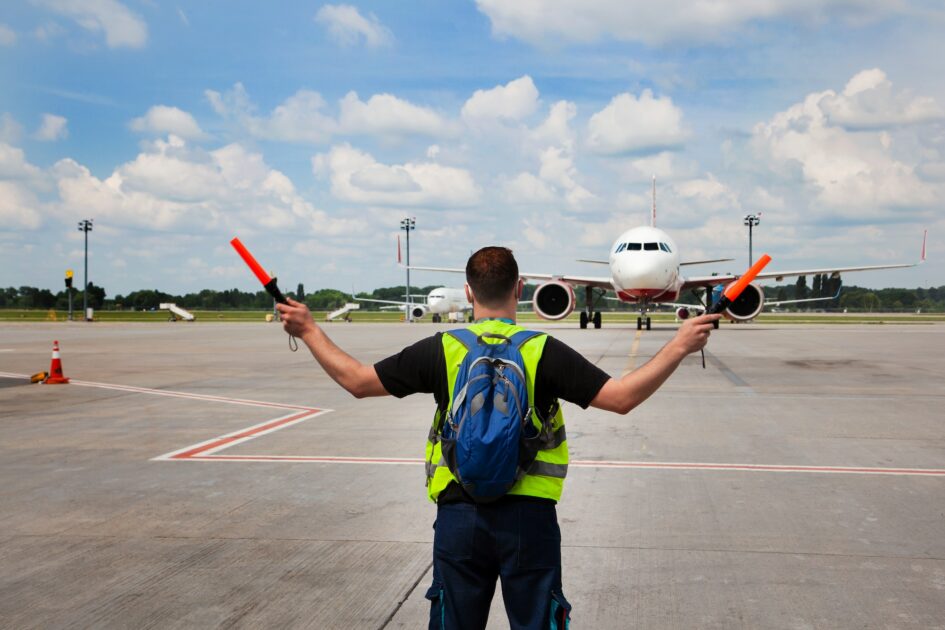 Air traffic controller at the Atlanta airport. The man salutes and guides the plane. Runway apron. Work