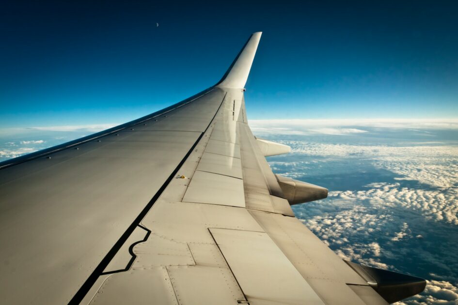 Airplane wing with clouds and blue sky