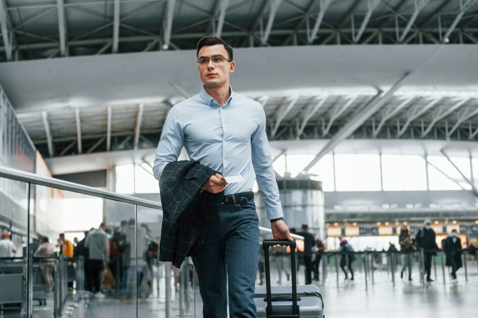 Front view. Young businessman in formal clothes is in the airport at daytime