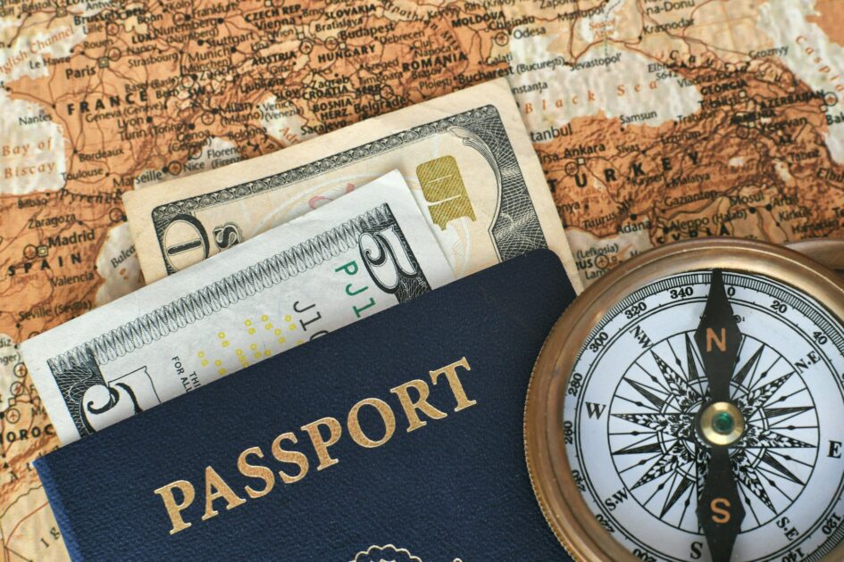 Close up of money cash in a passport with compass and map - travel concept
