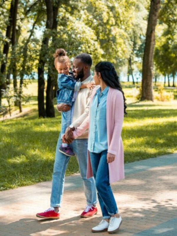 african american parents and daughter walking together in park
